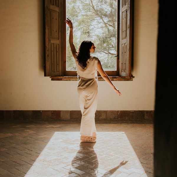 Serene woman meditating in a softly lit room with a peaceful expression.