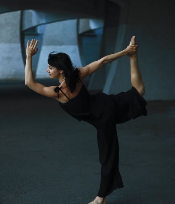 Woman in a graceful and calm yoga pose on a dark velvet background.